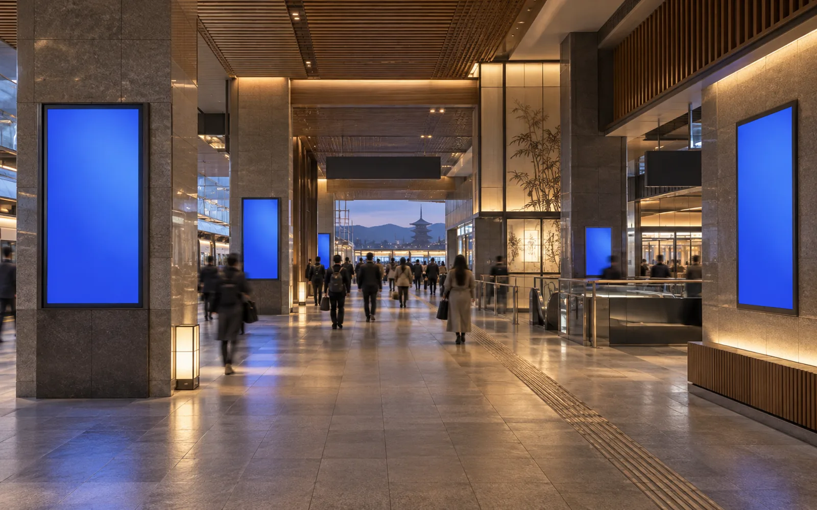 京都をイメージした夕方の駅コンコース。木と石の内装に並ぶ広告スクリーン